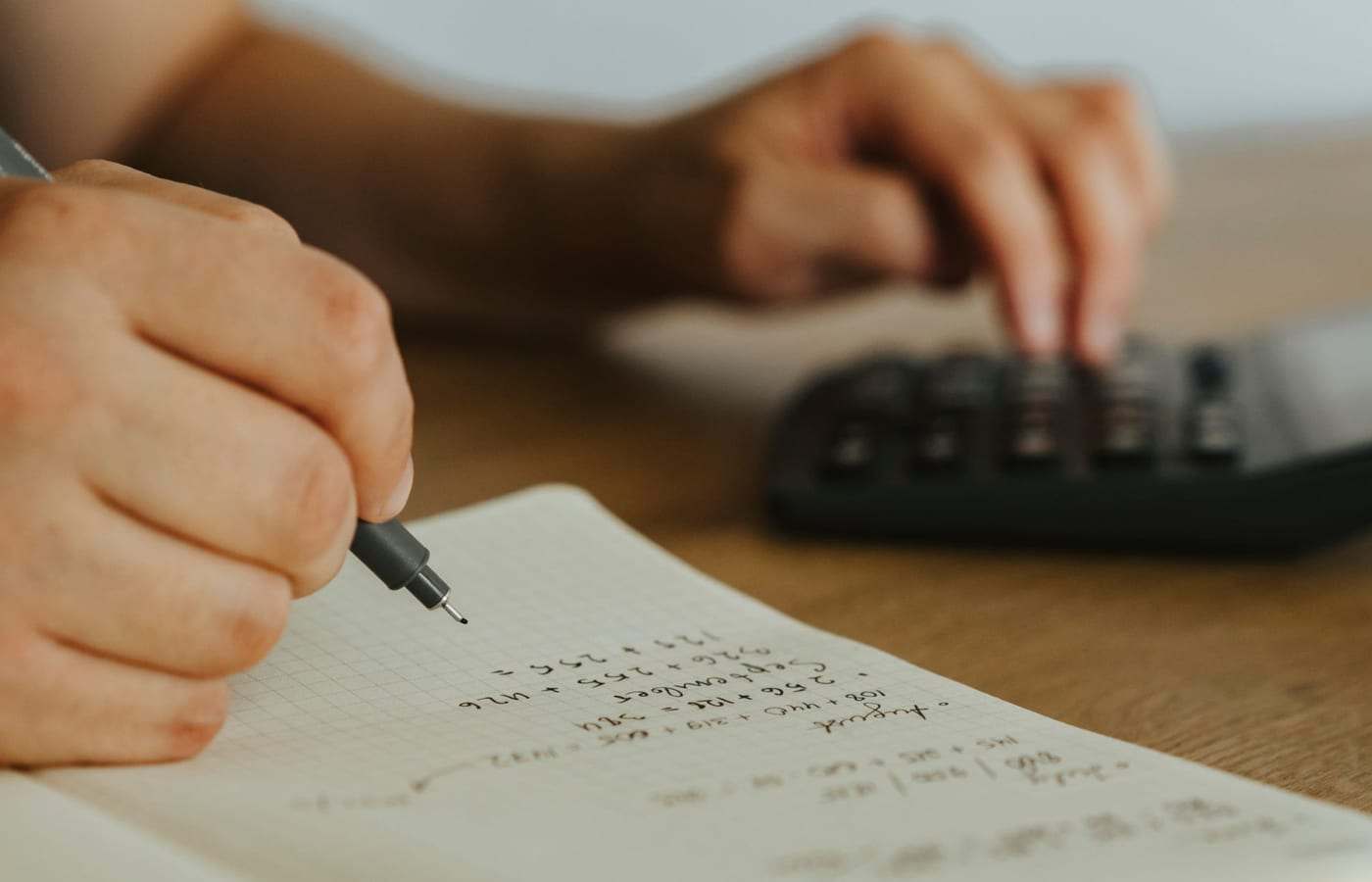 شخص يراجع أوراقاً وحسابات على طاولة بجانب حاسبة